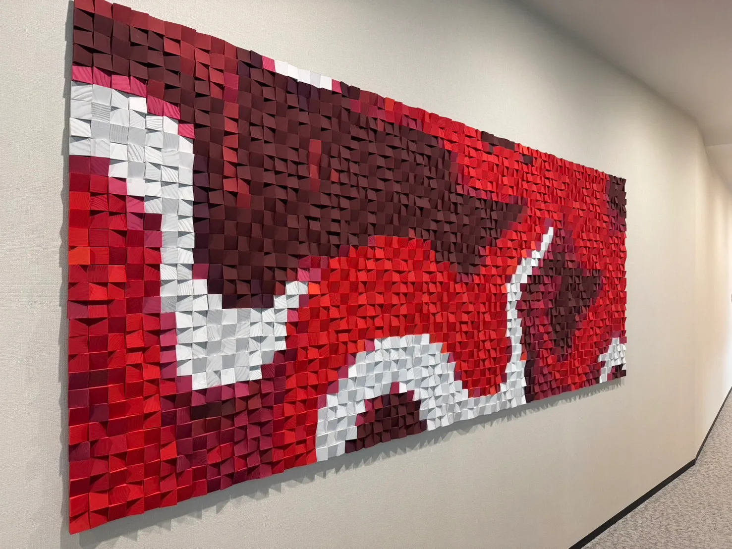 Large red and white wood mosaic logo mural running along a corridor at the Coca-Cola Thailand head office
